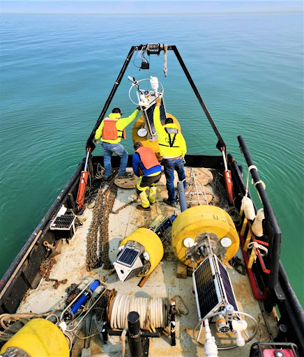Lakeshore Towing team placing navigational buoy in water