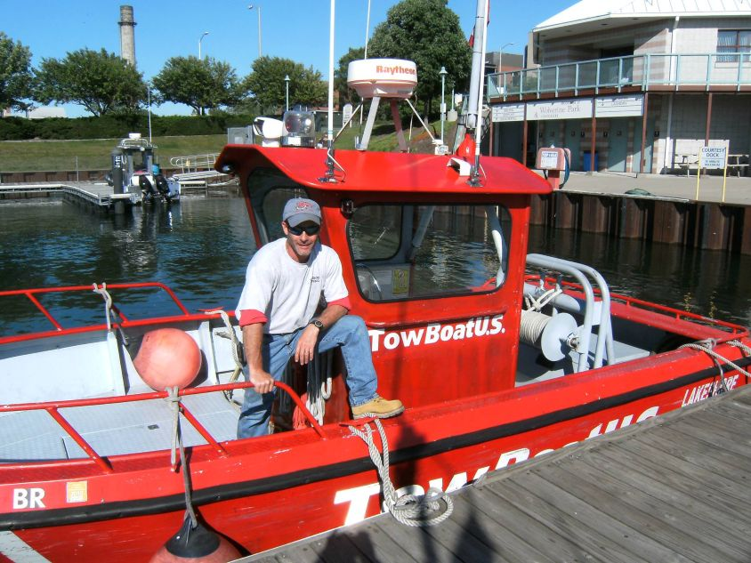 employee-standing-on-a-lakeshoring-towing-boat-in-the-water.png